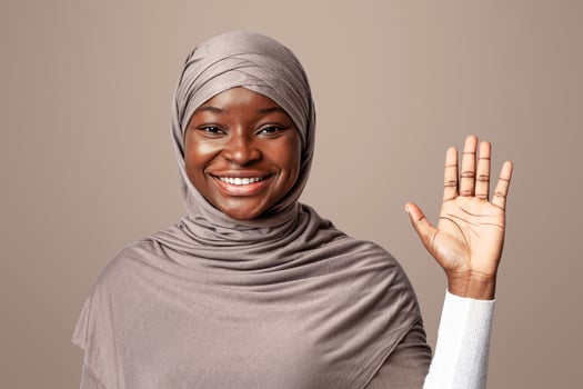 Hello Gesture. Friendly Black Muslim Lady In Headscarf Waving Hand At Camera, African Islamic Lady Gesturing Hi With Open Palm, Greeting Someone, Posing Over Light Background In Studio photo
