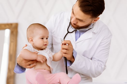Doctor Examining Little Baby On Medical Checkup Listening To Child's Heartbeat With Stethoscope Checking Heart And Lungs In Clinic. Toddler Patient Having Appointment At Pediatrician's Office photo