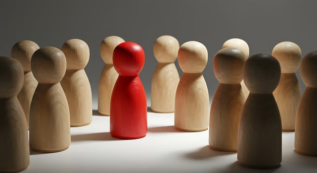 Red Wooden Figure Stands Out Among Natural Wood Figures in Spotl photo