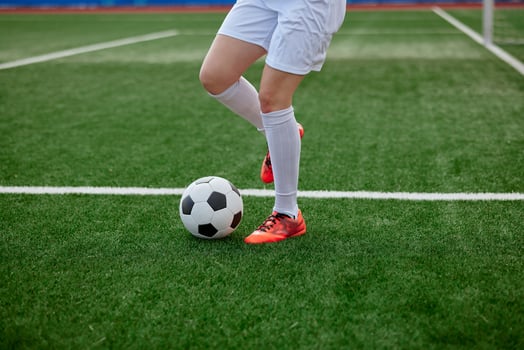 Female legs with soccer ball on green field, red cleats in training action. photo