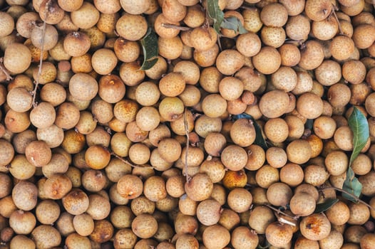 background with ripe longan. Exotic Asian fruits on counter in the market close-up photo
