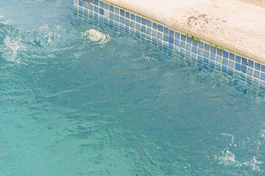 refreshing blue pool water with splashing detail, swimming pool corner with mosaic tiles and splashing water photo