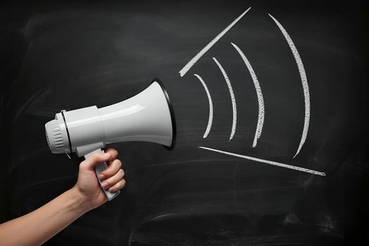 White megaphone with chalk sound waves on blackboard photo