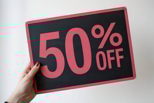 Hand with red nails holding black 50 OFF sale sign photo