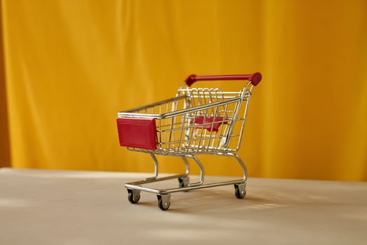 Miniature chrome shopping cart with red accents on yellow background photo