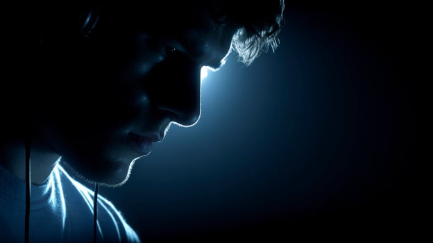 Person in Dark Room Wearing Headphones, Lit from Above photo