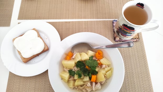 Chicken soup with potatoes, carrots and coriander, bread and herbal tea for healthy lunch dinner photo