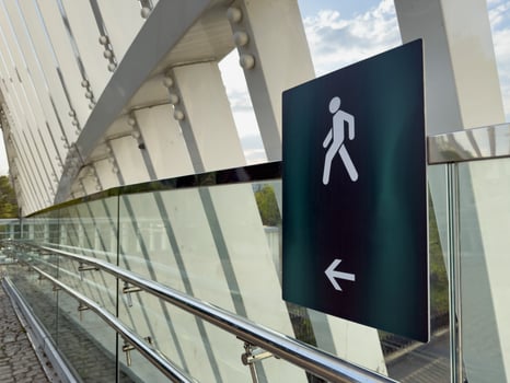 Modern architectural details of a pedestrian bridge featuring sleek glass panels, steel beams, and bold directional sign, showcasing urban minimalism and contemporary design photo