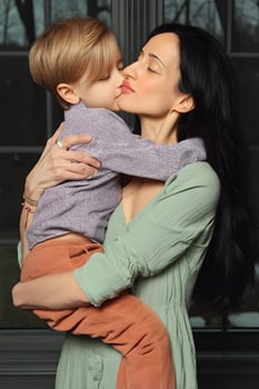 Tender Moment Mother and Young Son Embrace with a Sweet Kiss photo