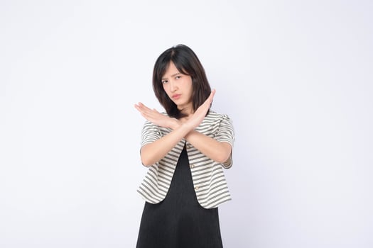 Southeast asian woman shows serious expression with crossed arms in gesture of refusal or advertising no sign in plain background photo