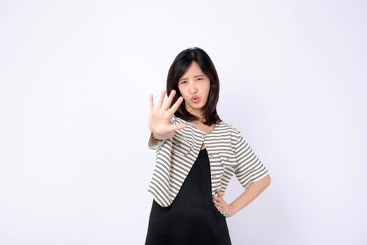 Southeast asian woman in advertising style poses with serious expression showing stop gesture with her hand in front of white background photo
