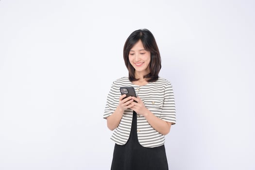 Southeast asian woman happily using mobile phone to access internet application in bright setting with casual striped jacket and black dress photo