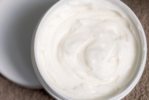 Opened Jar of face or body cream on brown towel top view, Lotion in Opened cosmetic Container photo