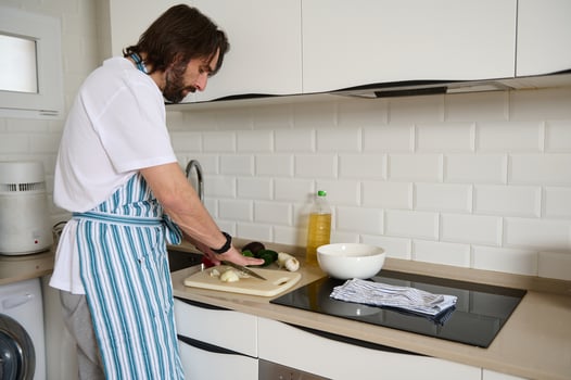 Man Preparing Healthy Salad in Modern Home Kitchen While Wearing Apron photo