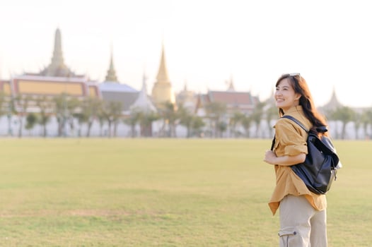 Southeast asian woman enjoys travel concept with bright smile while exploring historic temple area in warm sunlight, capturing joyful spirit of adventure and culture photo