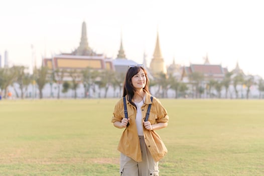 Southeast asian woman travel concept with backpack in historic park smiling happily during sunny day photo