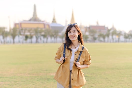 Southeast asian woman smiles happily while travel exploring historic site outdoors in sunny day, capturing joyful travel concept with cultural background and casual outfit photo