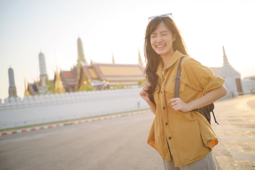 Southeast asian woman travel concept shows joyful woman smiling brightly while exploring cultural site in warm sunlight, capturing essence of travel and happiness photo