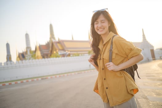 Southeast asian woman travel concept happy smiling with backpack near temple in warm sunlight photo