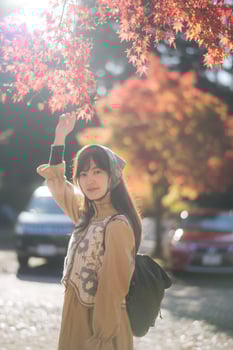 Southeast asian woman enjoys travel concept under bright autumn leaves wearing headscarf and backpack with peaceful expression in soft sunlight outdoors photo