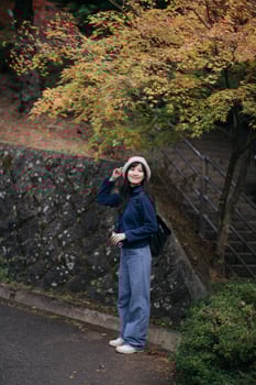 Southeast asian woman enjoys travel concept outdoors wearing casual clothes and hat standing near autumn trees with colorful leaves in peaceful natural setting photo