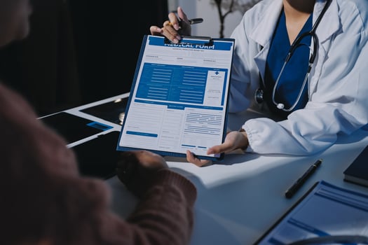 A doctor is holding a clipboard with a patient's medical records photo