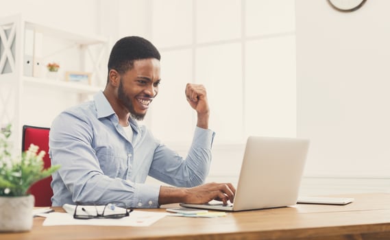 Happy excited businessman celebrate his success. Winner, black man in office reading on laptop, copy space photo