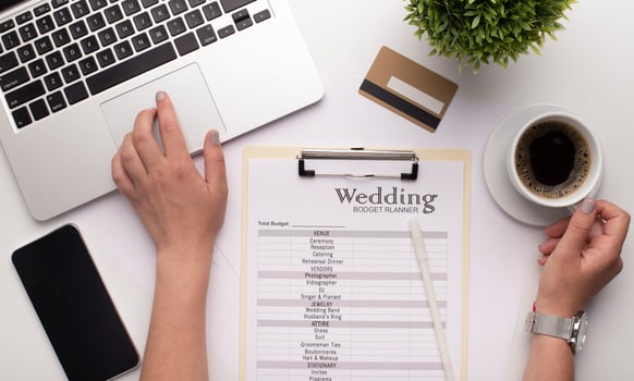 Wedding consultant constituting wedding plans and budget with laptop and smartphone, modern workplace photo