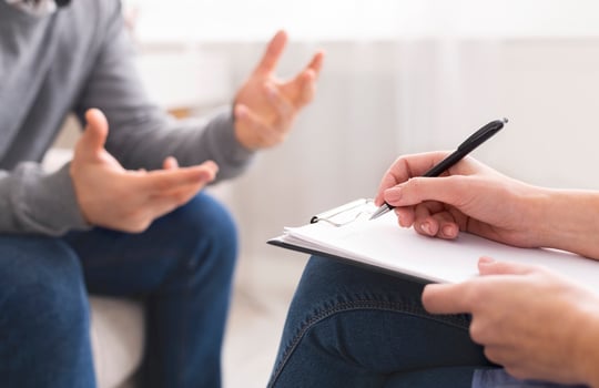Psychotherapist writing notes, giving diagnosis to emotional man patient at counseling session, free space photo
