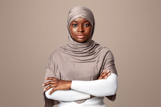 Serious Black Muslim Woman Standing With Folded Arms Over Light Background, Confident African Islamic Lady Posing In Studio, Religious Millennial Female In Headscarf Looking At Camera, Copy Space photo