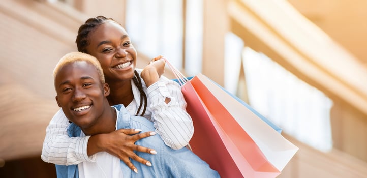 Leisure, free time and purchase. Smiling african american couple in casual with paper bags having fun near store, sun flare photo