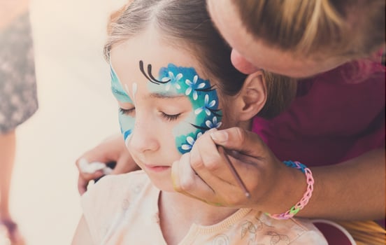 Child face art made to little girl. Blue butterfly painting. Children birthday party entertainment photo