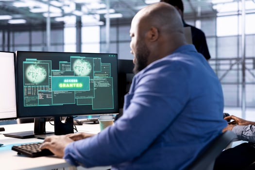 Access granted notification on monitor received by man reconfiguring server hub, optimizing it. African american data center IT expert using PC to successfully eliminate all errors photo
