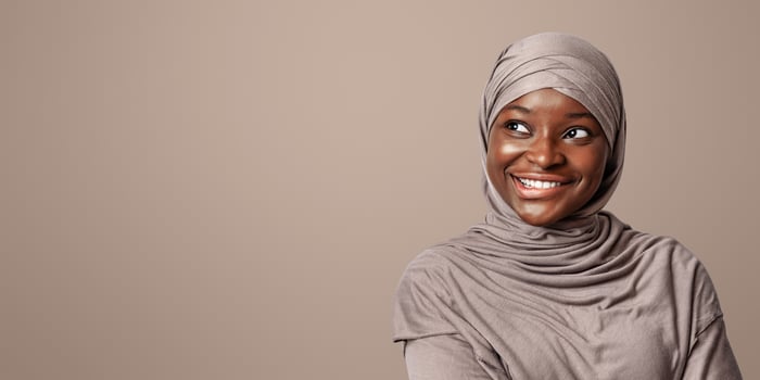 Curious black muslim woman in hijab looking at copy space and biting lip with excitement, pensive smiling african islamic lady in headscarf thinking about interesting offer, panorama with free place photo