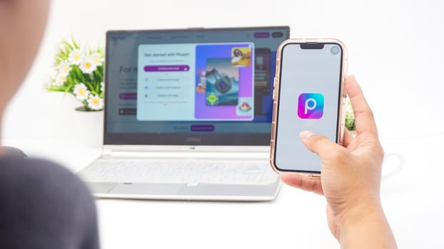 Yogyakarta, Indonesia, 2025 - Man holding smartphone that shows front page of Picsart, a creative editing platform application on the screen isolated on white background photo