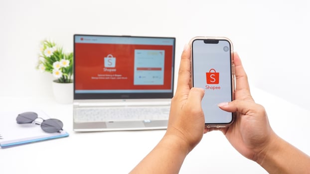 Yogyakarta, Indonesia, 2025 - Man hand holding smartphone that shows front page of Shopee, e-commerce or online shopping platform application on the screen isolated on white background photo