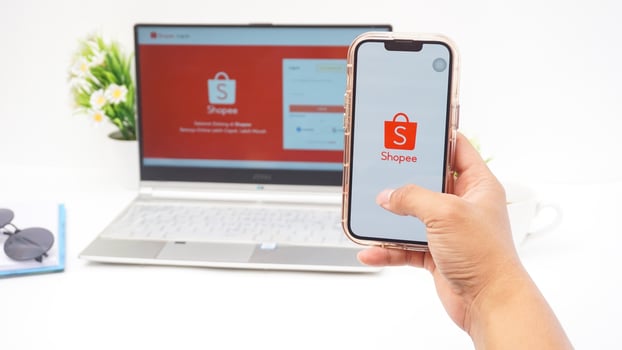 Yogyakarta, Indonesia, 2025 - Hand using smartphone that shows front page of Shopee, e-commerce or online shopping platform application on the screen isolated on white background photo