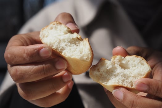 Freshly baked bread being torn apart in a sunny outdoor setting photo