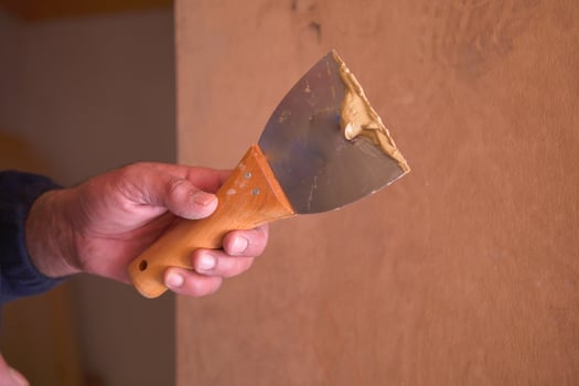 Skilled worker applies putty with a knife to a wood surface photo