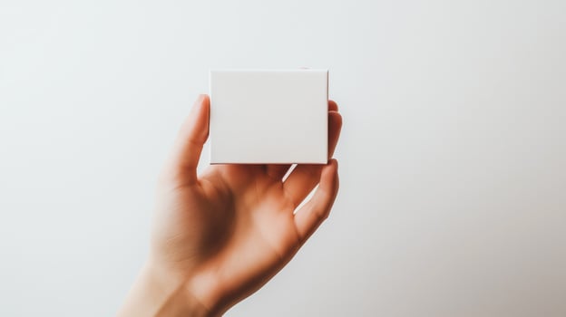 Hand holding small white box against wall. photo