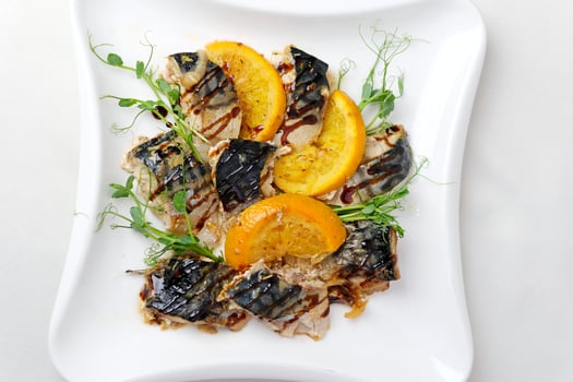 Grilled mackerel fish oranges and rosemary served on a stylish plate. photo