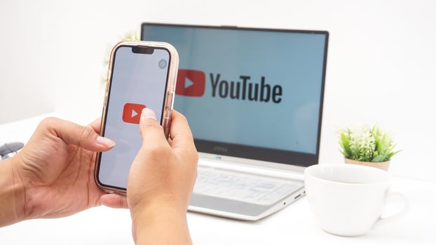 Yogyakarta, Indonesia, 2025 - Hand with smartphone that shows icon of Youtube platform application on the screen isolated on white background photo
