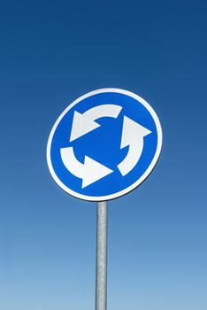 Roundabout crossroad road traffic sign against blue sky photo