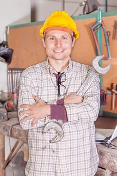 portrait of young metalworker with yellow protective helmet and a wrench photo