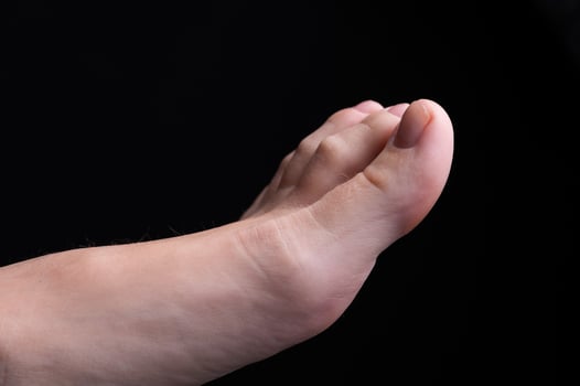 Barefoot feet, on black background. Close-up shot of healthy beautiful female feet. Health and beauty concept. Top view of human foot with neutral manicure or pedicure photo