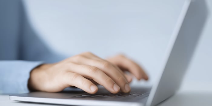 A person typing on a laptop computer photo