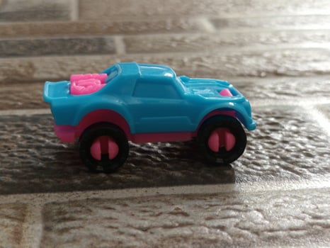 A Small Blue and Pink Toy Truck on a Wet Tiled Surface. photo