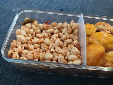 Roasted Peanuts and Pineapple Tarts in a Clear Compartment Container. photo