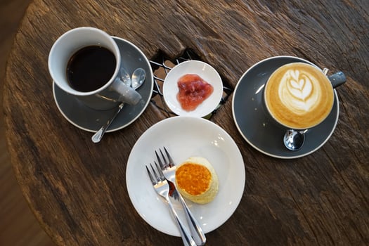 Porcelain cup of hot black coffee and Latte served with butter plain scone and berry jam on wooden table photo