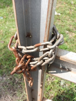 Rusty Metal Chain Wrapped Around a Weathered Metal Post. photo